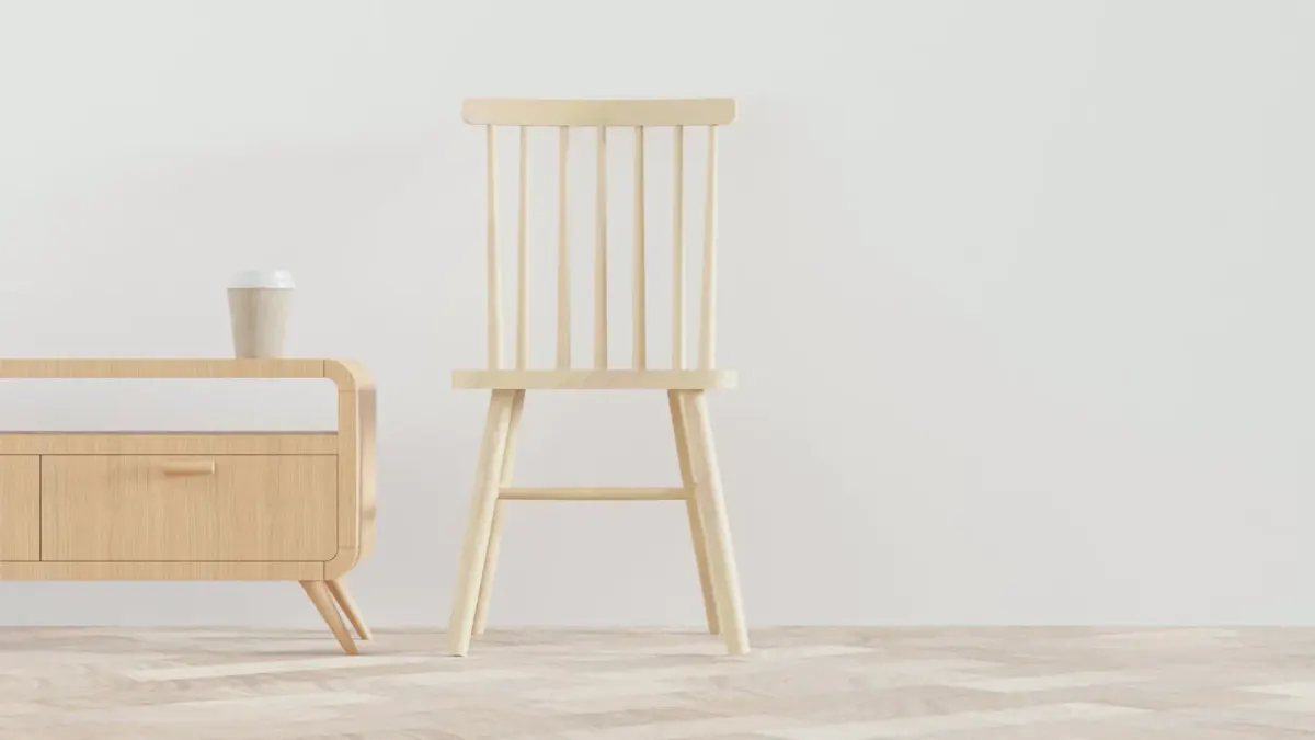 A dog mid-chew on a wooden chair leg in an otherwise empty living room