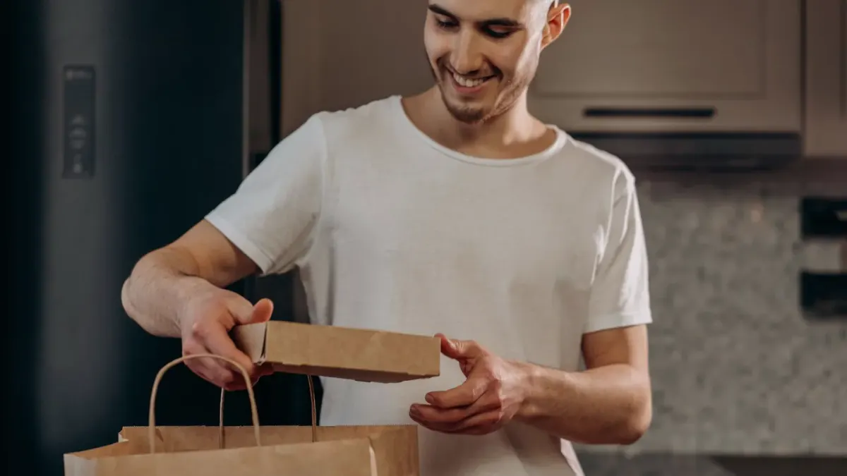 A dog owner opening a small delivery box of chew supplements next to a bowl of dog food