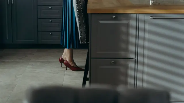 A dog trailing a woman's heels as she moves through her kitchen