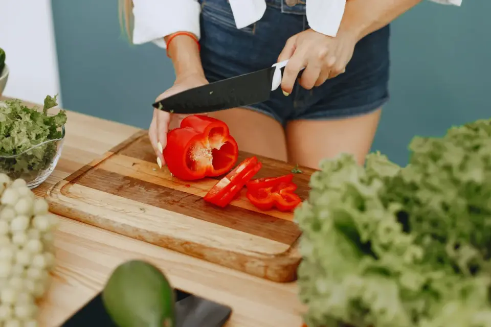 A halved avocado on a cutting board while a dog watches from the kitchen floor