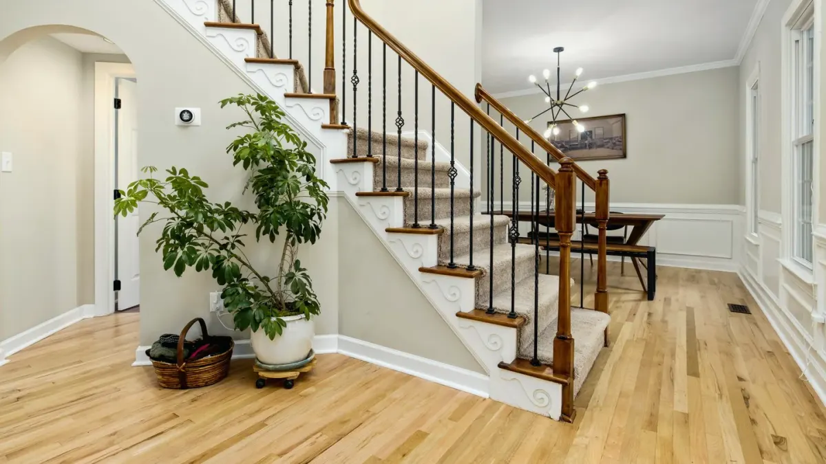 A middle-aged golden retriever pausing at the bottom of a staircase