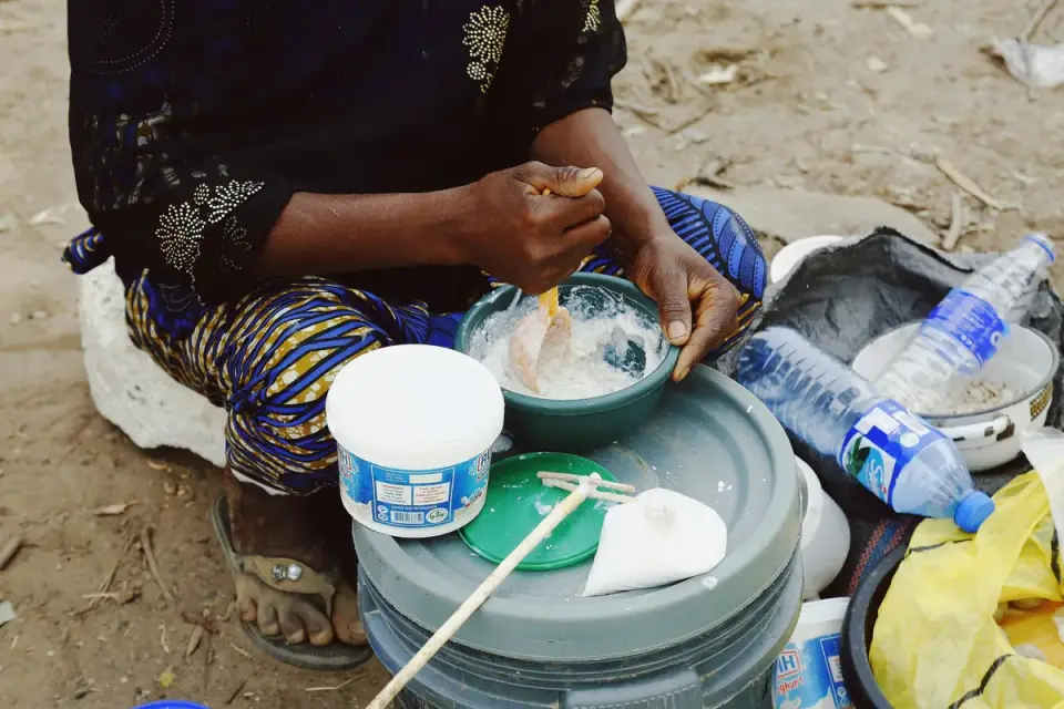 A person blending two types of dog food together in a travel bowl at a campsite