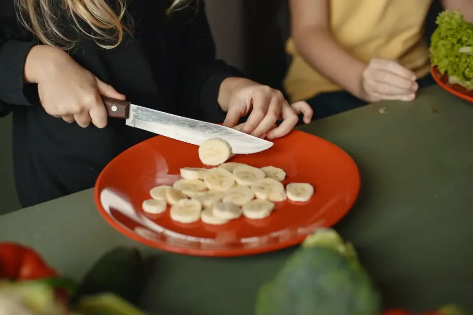 A person&#x27;s open hand offering small banana slices to a dog