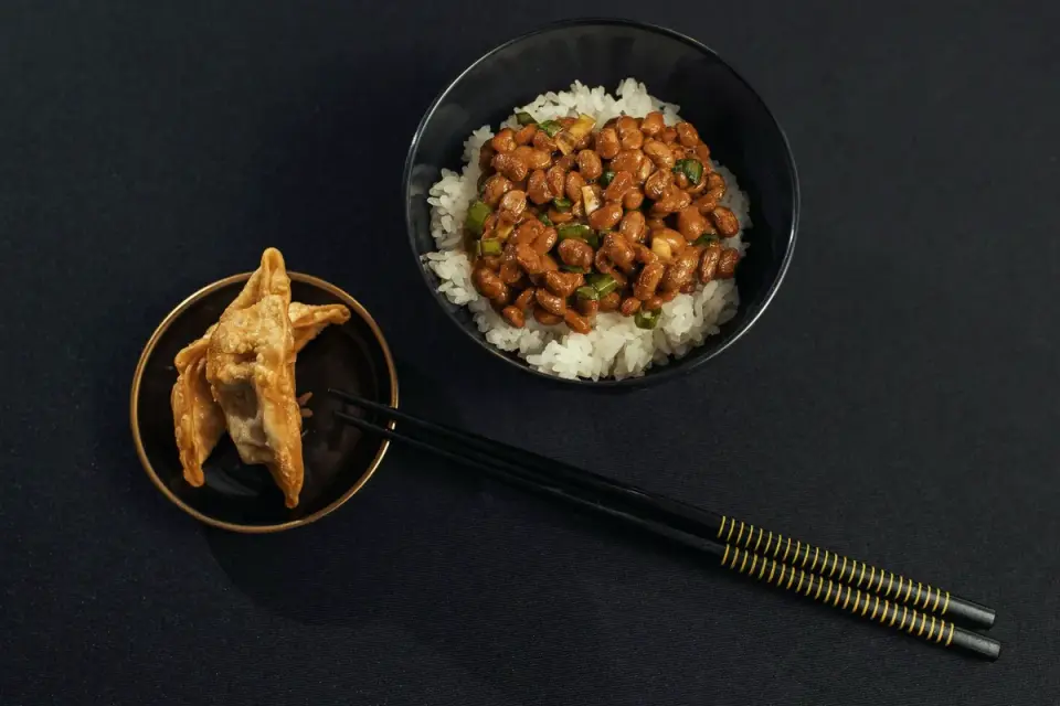 A small bowl of steamed green beans set beside a dog&#x27;s food bowl