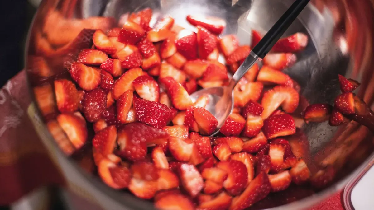 Fresh strawberries sliced into small pieces next to a dog's bowl