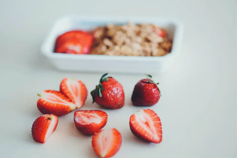 Golden retriever investigating a small bowl of sliced strawberries on a kitchen floor