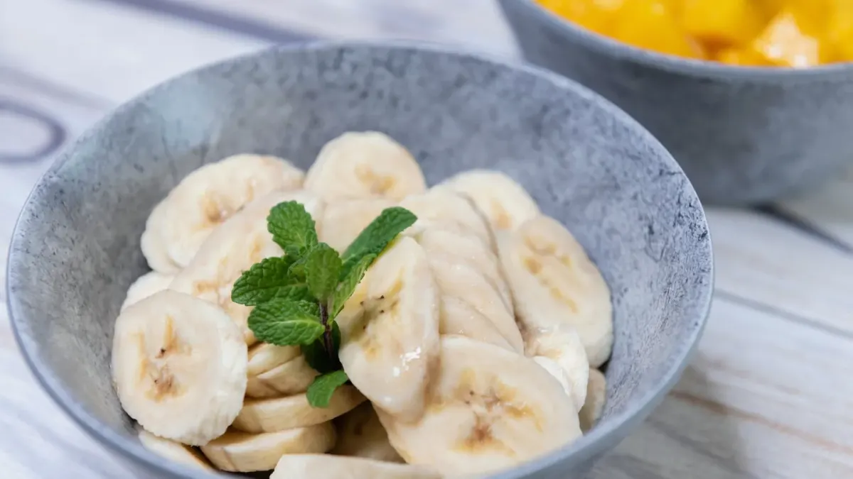 Sliced banana pieces set beside a dog's stainless steel food bowl